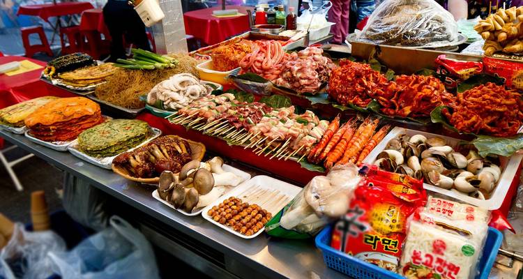 Levendige Koreaanse straatvoedselkraam vol met noedels, spiesjes, kimchi en zeevruchten.
