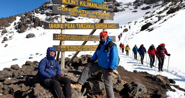 Mount Kilimanjaro-klimmers verzamelen voor foto's bij het beroemde felicitatiebord van Uhuru Peak te midden van besneeuwde vulkanische rotsen.