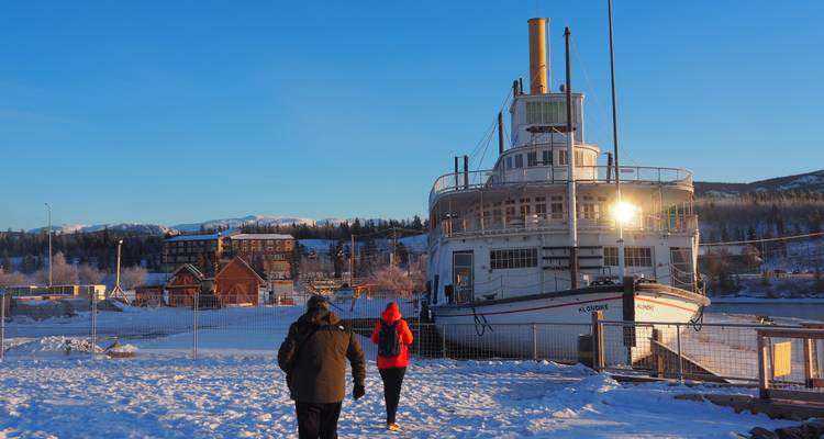 Des gens marchant vers un bateau à aubes amarré par une journée enneigée.