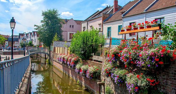 Bunte Blumen und Häuser entlang eines schmalen Kanals.