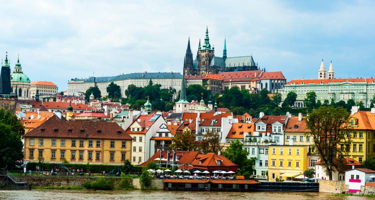 Vue panoramique d'une ville avec un château célèbre et une rivière au premier plan.