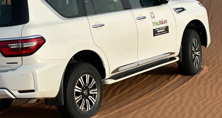 Weißes Geländefahrzeug auf einer Sanddüne mit einem Logo.