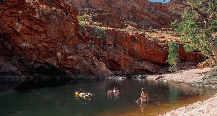 Menschen, die in einem natürlichen Wasserloch schwimmen und treiben, umgeben von Klippen.