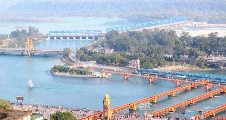 Luchtfoto van Haridwar met bruggen en drukke rivieroever.