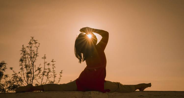 Silhouet van een persoon die yoga doet tijdens zonsondergang.