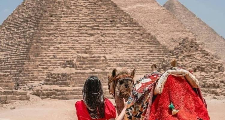 Une personne avec un chameau devant les pyramides.