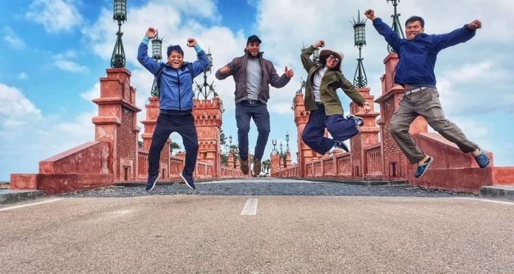 Quatre personnes sautant sur un pont avec des tours ornementales.