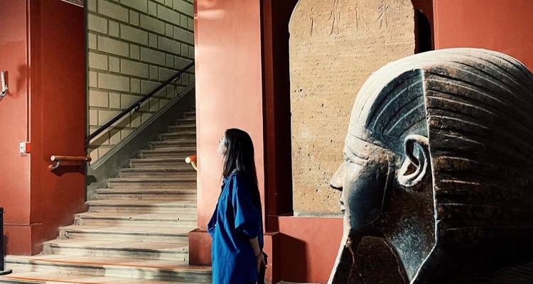 Personne dans un musée debout à côté d'une statue antique.