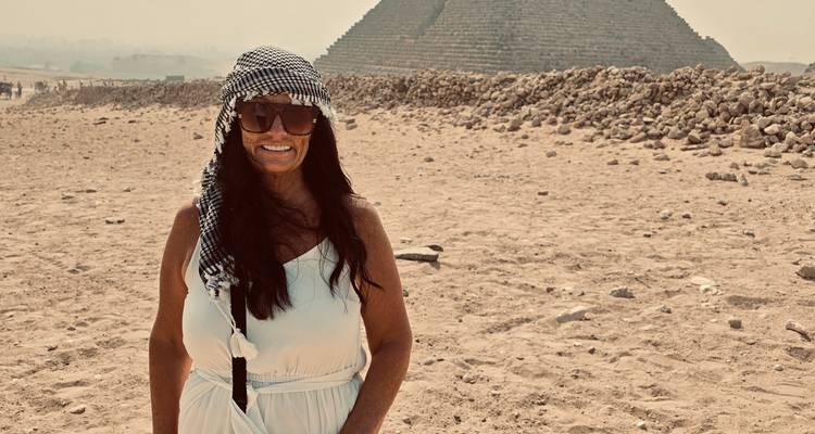 Femme posant devant la pyramide sous un ciel brumeux.
