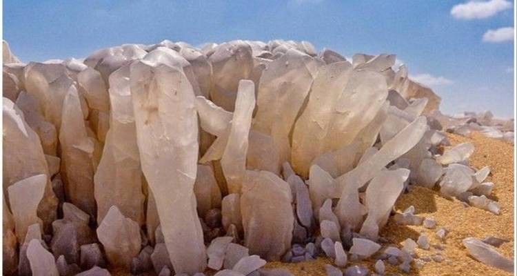 Formations cristallines émergeant du sable dans un paysage désertique.