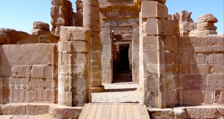 Entrée d'un site historique avec des murs en pierre et des hiéroglyphes sculptés.