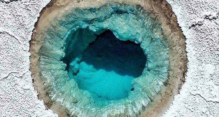 Vue aérienne d'un bassin naturel circulaire aux eaux turquoise.