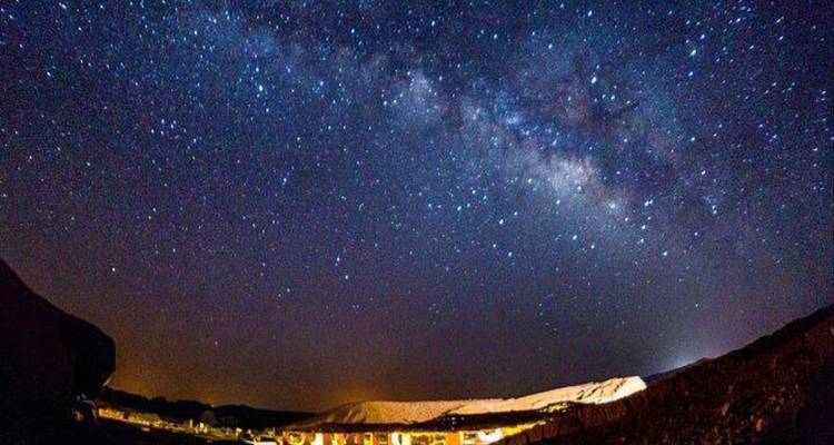 Ciel nocturne étoilé au-dessus d'un paysage désertique.