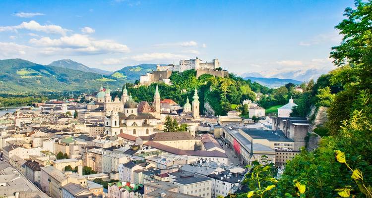 Panoramablick auf die Stadt Salzburg mit einer Festung auf einem Hügel.