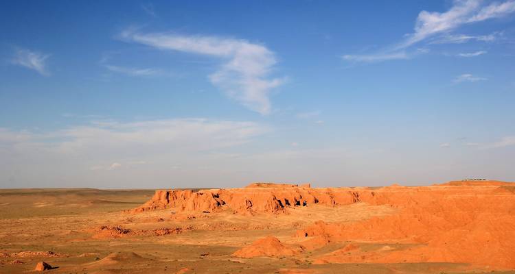 Uitgestrekte rode rotsformaties onder een blauwe lucht.