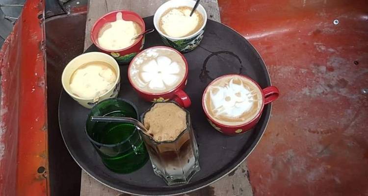 Tablett mit Tassen verschiedener Kaffeesorten auf einem Holztisch.