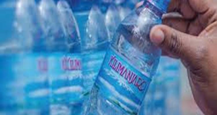 Gros plan d'une main tenant une bouteille d'eau Kilimanjaro.
