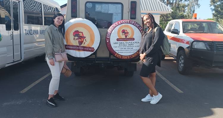 Deux personnes debout devant un véhicule de safari avec des panneaux publicitaires.