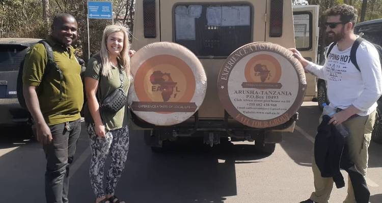 Trois personnes posant avec un véhicule de safari.