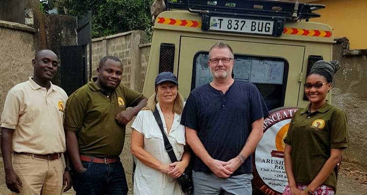 Groupe de touristes et de guides locaux posant près d'un véhicule.