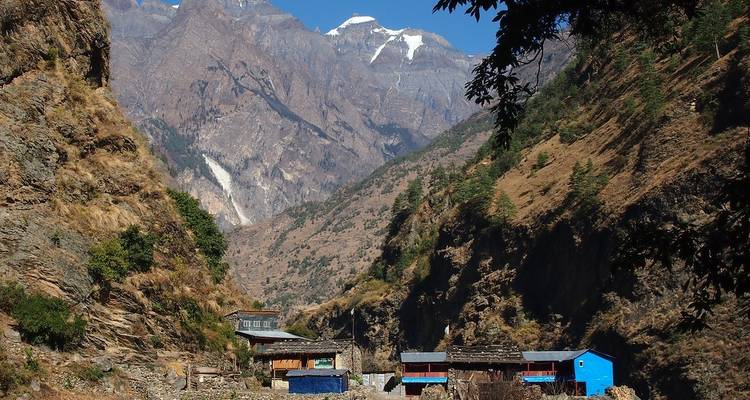 Bergtal mit traditionellen Häusern und umgebender Vegetation.