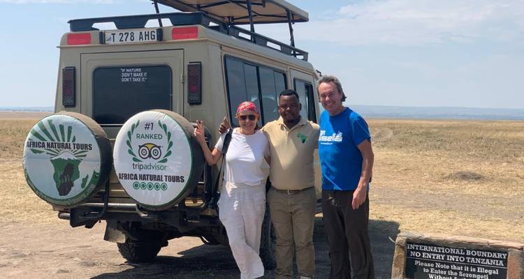 Toeristen met een safarivoertuig in een grasachtig gebied.