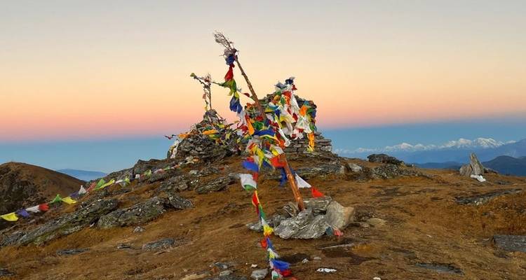 Bergtop met gebedsvlaggen tegen een kleurrijke hemel.