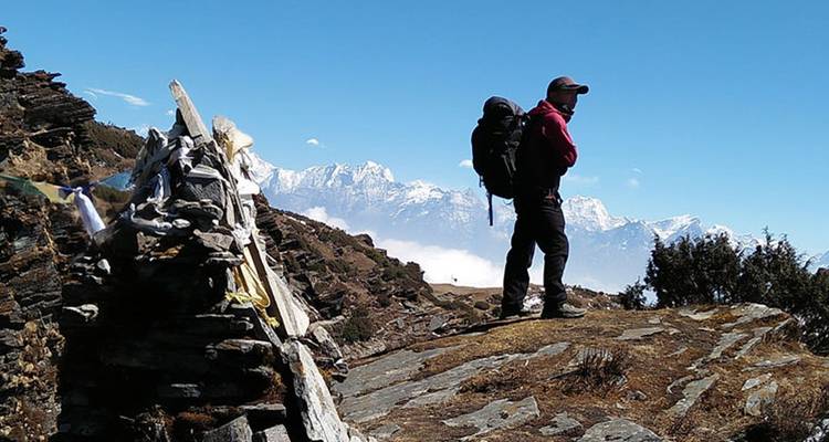 Wandelaar die op een rotsrichel staat met uitzicht op de bergen.