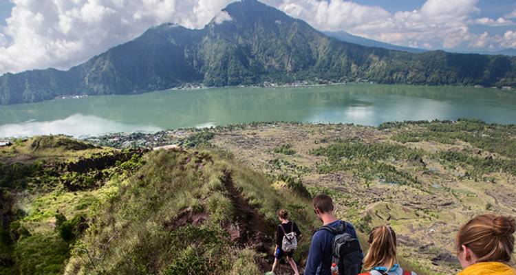 Randonneurs marchant le long d'une crête avec un lac et une montagne en arrière-plan.