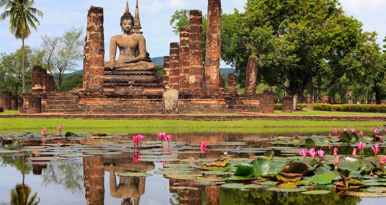 Statue de Bouddha ancienne avec reflet d'étang de lotus.