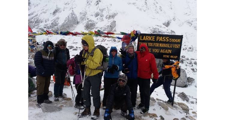 Groupe de randonneurs au col de Larke avec des montagnes enneigées en arrière-plan.