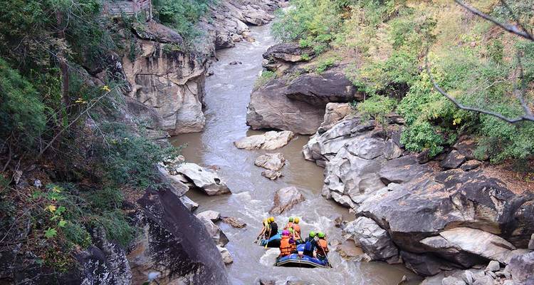 Los navegantes de aguas bravas avanzan por un estrecho desfiladero rocoso rodeado de densa vegetación de selva en el norte de Tailandia.