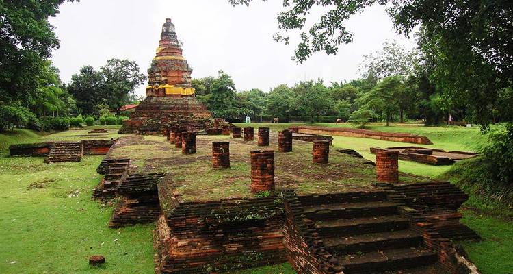 Ruinas de antiguo chedi de ladrillo rodeadas de césped verde y árboles en Wiang Kum Kam cerca de Chiang Mai.