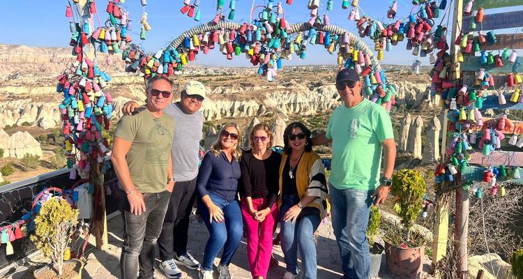 Group posing in front of a decorative arch with a scenic backdrop.