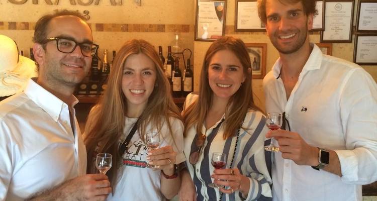 A group of friends enjoying drinks at a wine tasting event, posing, and smiling.