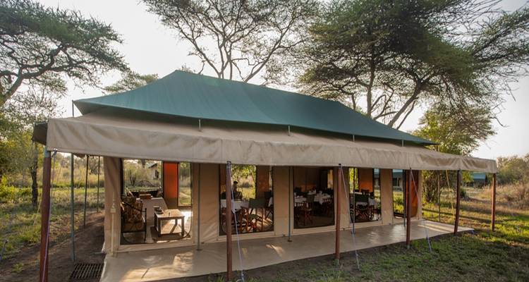 Tente safari haut de gamme avec coin repas en pleine nature.