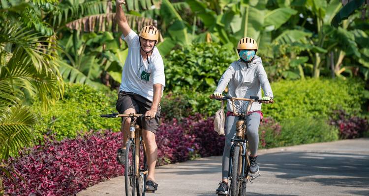 Homme et femme faisant du vélo sur un sentier entouré d'une végétation luxuriante.