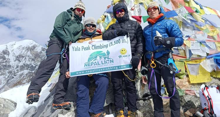 Gruppe von Bergsteigern auf einem Gipfel mit bunten Gebetsfahnen.