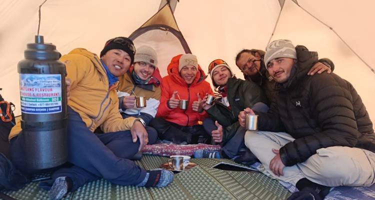 Gruppe von Personen in einem Zelt beim Teetrinken.