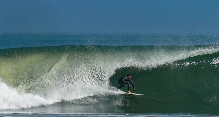 Surfista montando una ola en un día despejado.