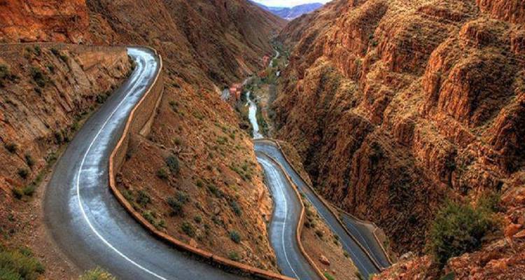 Kronkelende bergweg die zich slingert door steile, ruige rode rotscanjonwanden