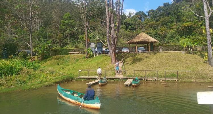 Un hombre en una canoa en un lago tranquilo con otros en el fondo cerca de un pequeño muelle.