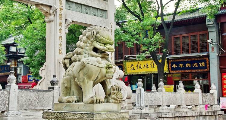 Stone lion statue in a traditional Chinese market setting.