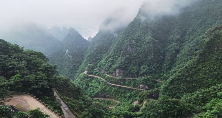 A winding road through lush, mist-covered mountains.