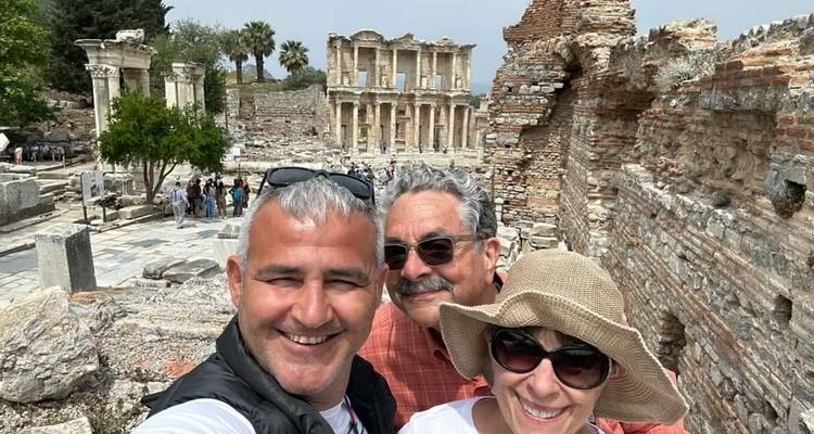 Drie mensen voor oude ruïnes.