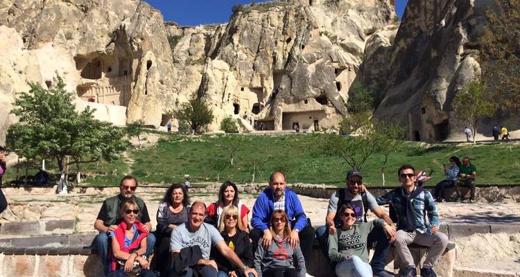 Groep poseert voor rotsformaties met grotwonin­gen.