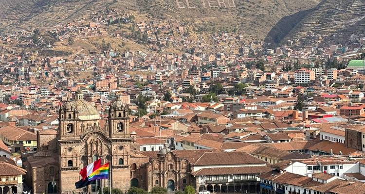 Vue panoramique de la ville de Cusco avec une cathédrale et des drapeaux.