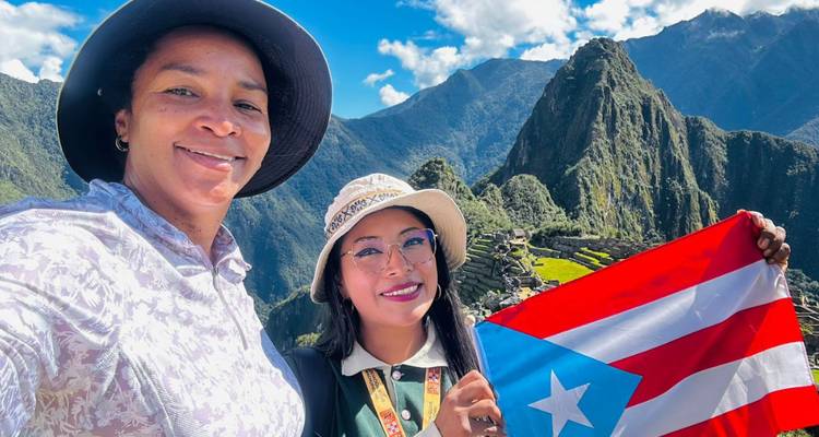 Deux femmes prenant un selfie au Machu Picchu avec un drapeau coloré.