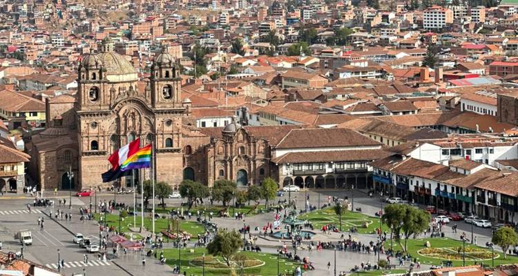 Vue panoramique de Cusco avec un grand drapeau sur la place de la ville.