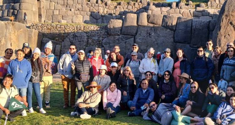 Grand groupe de touristes posant devant d'anciennes structures en pierre.